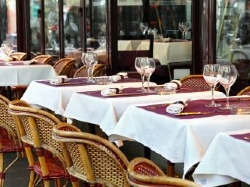 Line of white-tableclothed tables in a French restaurant terrace
